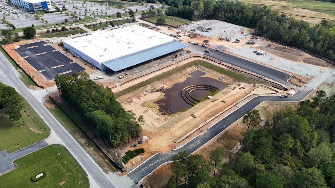 Aerial view of construction site with building and pond.