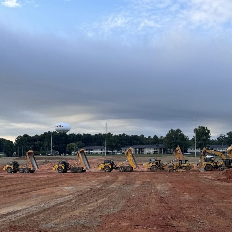 Construction Vehicles A lineup of construction dump trucks with raised beds at a red clay site in Auburn, Alabama