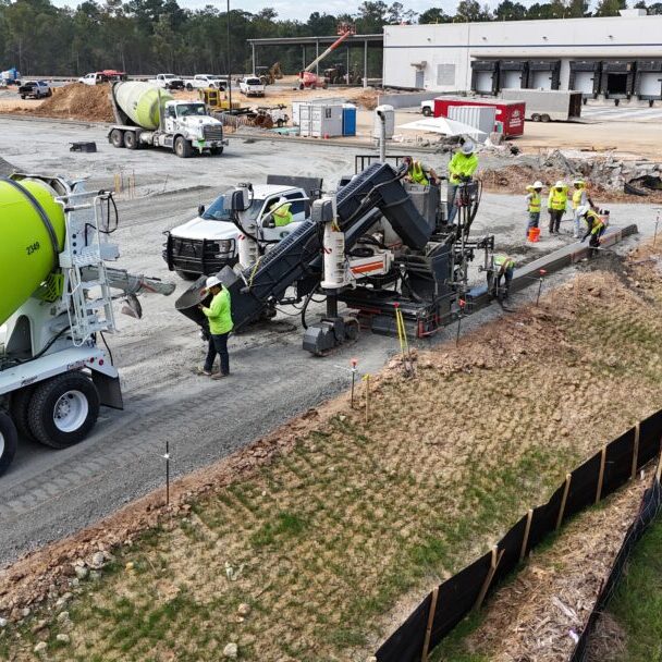 Concrete Paving Operations with Mixer Trucks Concrete mixer trucks and paving crews pouring concrete near a distribution center