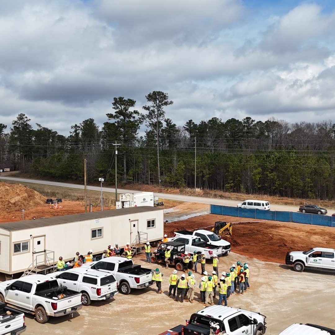 Construction Site Safety Meeting with Workers Construction workers gathered for a safety meeting next to jobsite trailers and trucks