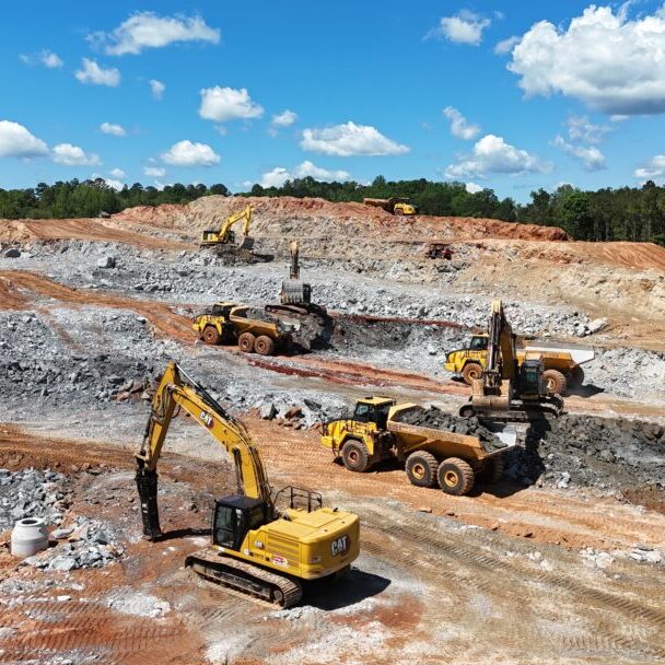 Excavators and Dump Trucks at Rock Quarry Site Excavators and dump trucks moving rock at active quarry or mining construction site