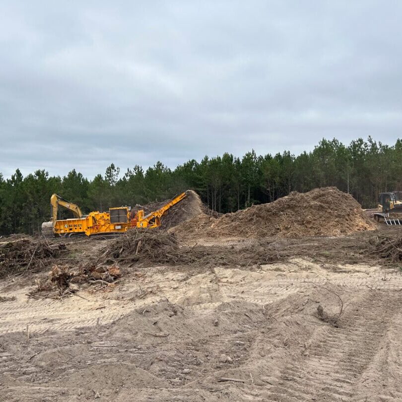 Wood Grinding and Land Clearing Equipment Yellow wood grinder machine processing land clearing debris at construction site