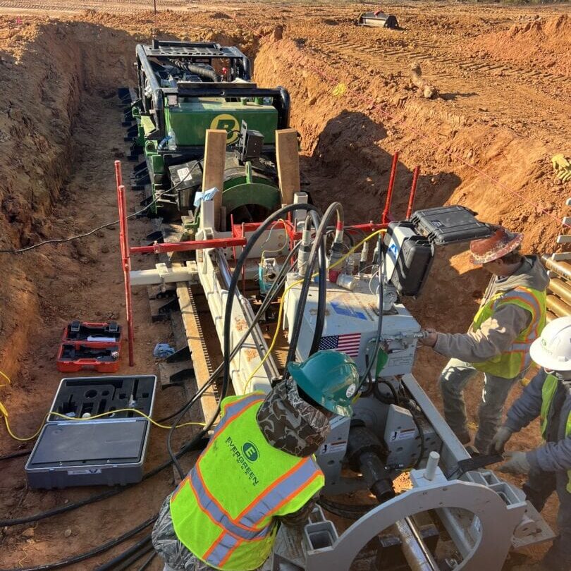 Crew Working with Jack and Bore Machine in Excavation Construction crew operating jack and bore machine inside trench at underground utility project