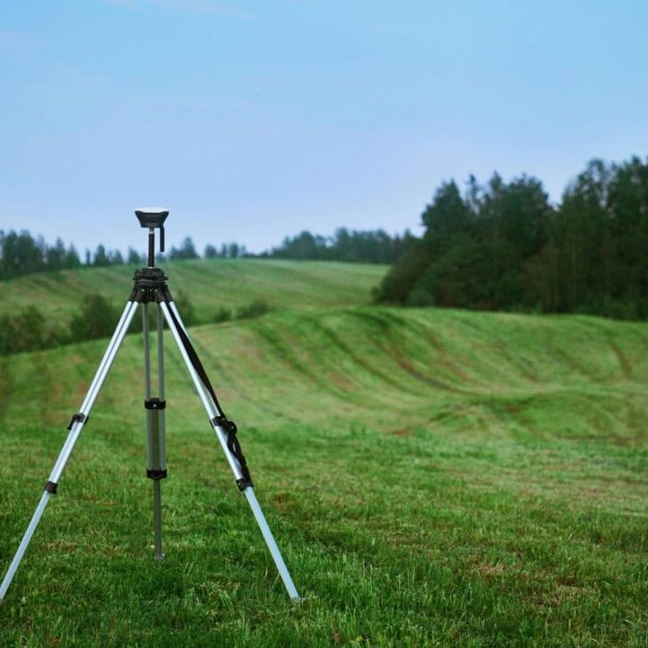 Survey Tripod Set Up in Open Green Field Survey tripod standing in green open field ready for land surveying measurements