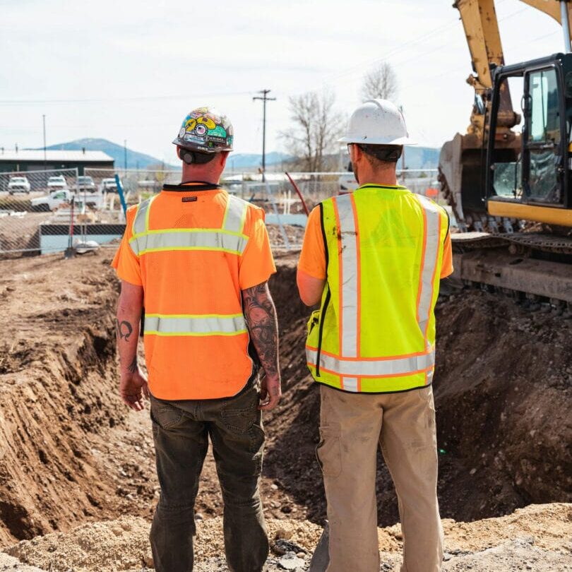 Construction Supervisors Inspecting Excavation Work Two construction supervisors inspecting excavation progress at site with CAT excavator