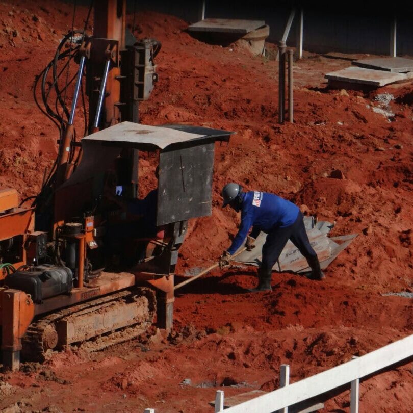 Worker Operating Equipment on Red Clay Site Construction worker operating drilling equipment on red clay site